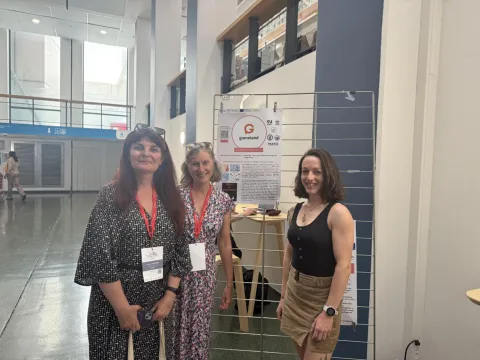 Elisabeth Richard, Christine Evain and Madelyn Lines posing in front of the GAMEland poster.
